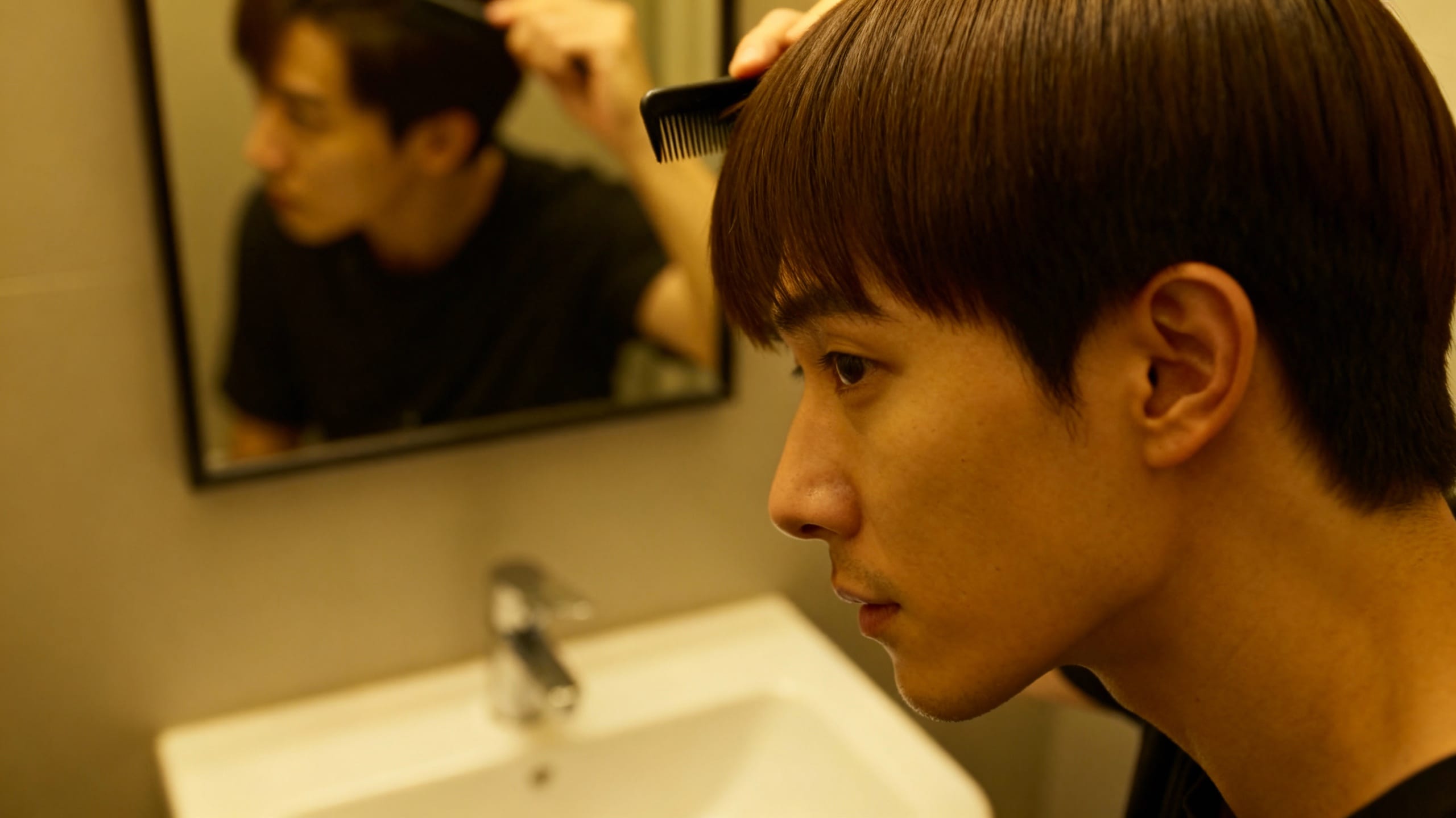 man styling his short straight hair in a mirror